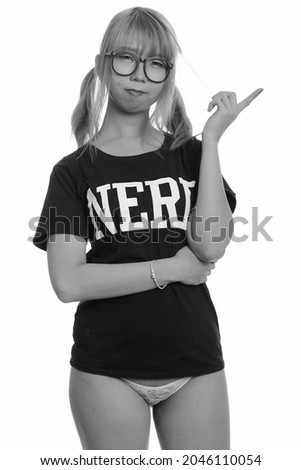 Studio shot of young Asian woman as nerd with eyeglasses isolated against white background in black and white