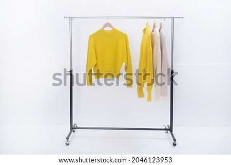 Four knitted warm sweaters on white hangers.