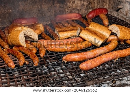 Grilled sausages on grill with smoke and flam