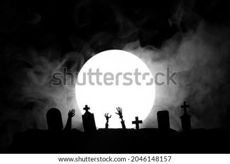Halloween. Cemetery with graves and the dead stretch their hands up against the background of the moon with fog.