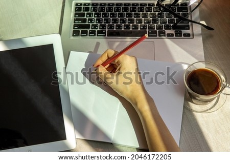 Hand of business woman writing on paper at her workstation. business concept.