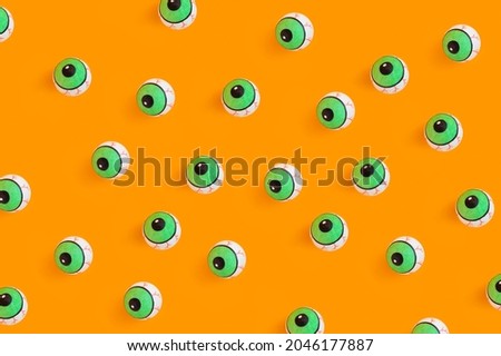 Halloween concept with human doll eyes on orange background