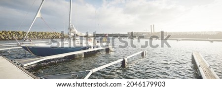 Blue sloop rigged yacht (for rent) moored to a pier in marina on a clear day. Sweden. Vacations, sport, amateur recreational sailing, cruise, regatta, transportation, nautical vessel Royalty-Free Stock Photo #2046179903