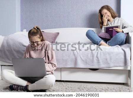 Two girls laugh at picture in the tablet.Time for rest and communication of friends