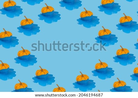 Trendy autumn pattern fresh pumpkin with dripping and melting paint on a pastel blue background. Minimal Autumn, Halloween or Thanksgiving concept background. Copy space