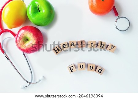 Top view wood block wording Healthy Food,fruit orange,lemon,red apple
green apple and stethoscope on clear background.For Healthy Food Concept.