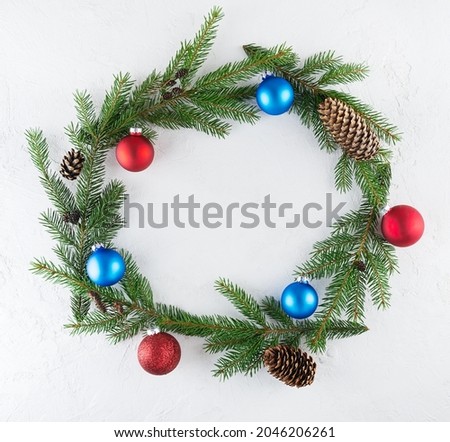 A wreath of fir branches, decorated with Christmas balls and cones on a white background. Christmas and New Year concept, top view.