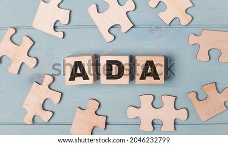 Blank puzzles and wooden cubes with the text ADA  lie on a light blue background.