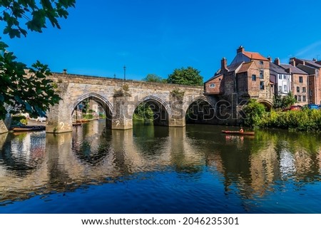 A view through the tree lined shore towards the Elvet Bridge in Durham, UK in summertime Royalty-Free Stock Photo #2046235301