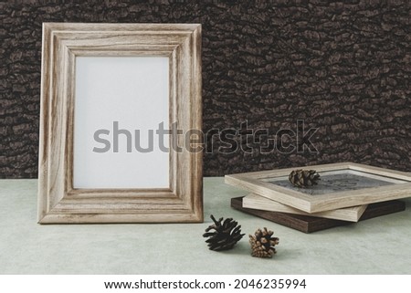 Empty wooden frame in forest style composition. Bark background and cone.