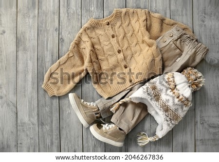 Knitted cardigan,  jeans and hat flat lay on wooden background. Baby autumn clothes. Boy's apparel set.Child's clothing top view.Outlook collection vintage wear. Royalty-Free Stock Photo #2046267836