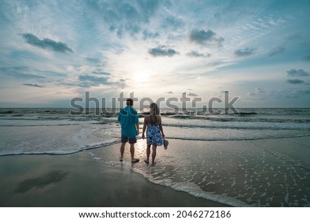People walking on the beach. Couple standing on the beautiful beach at sunrise. Friends relaxing on moody beach. Jekyll Island, Georgia, USA. Royalty-Free Stock Photo #2046272186