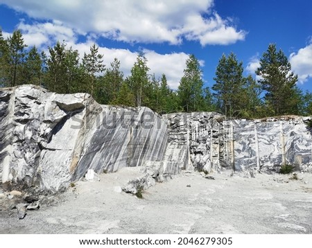 Italian quarry with smooth cuts and cuts during the extraction of marble in the Ruskeala Mountain Park on a sunny summer day.