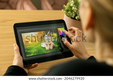 woman photographer using photo editing app on digital tablet