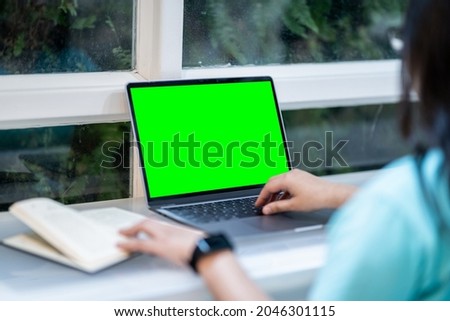 Close-up of businessfemale wearing smartwatch casual working with laptop computer with empty green screen and book with coffee cup and smartphone in at the cafe, Business Lifestyle communication