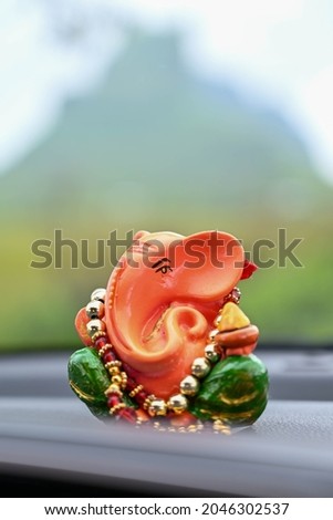 Ganesh idol on car dashboard with mountain in background
