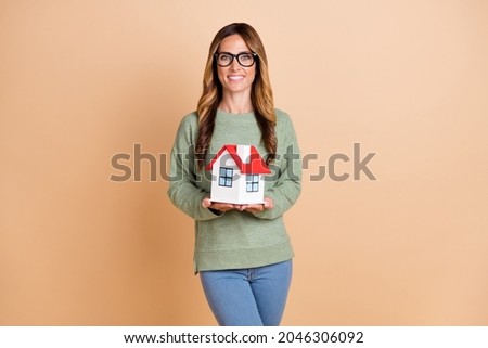 Photo portrait female agent wearing glasses smiling keeping little house isolated pastel beige color background