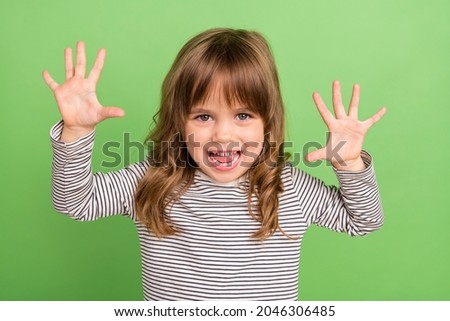 Photo of funny small blond hair girl hands up wear striped shirt isolated on green color backgound