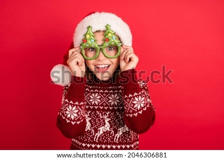 Portrait of attractive cheerful girl touching wearing festal specs eve christmastime isolated over bright red color background