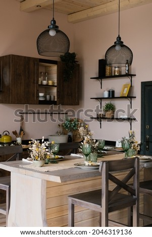 Wooden bar counter with wooden chairs in the interior of the kitchen dining room in the Scandinavian style with decor and hanging chandeliers above the table
