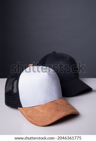 Two trucker caps on the table for brand design application. Tricolor cap and all black cap for mockup logo design. Royalty-Free Stock Photo #2046361775