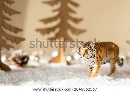 Figurine of tiger, wooden fir trees in snow on beige background. Tiger symbol of the Chinese new year 2022. Christmas greeting card