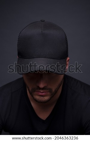 Man wearing all black cap in studio photo for branding application. Full black cap for logo Mockup Royalty-Free Stock Photo #2046363236
