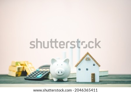 House and and piggy bank and gold bar and calculator and bar graph with growing value put on the account book on pink vintage background, Saving money and loan for investment on real estate concept. Royalty-Free Stock Photo #2046365411