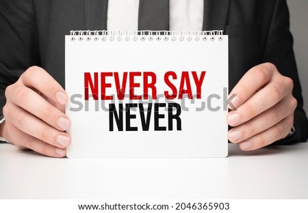 Businessman holding sheet of paper with a message NEVER SAY NEVER
