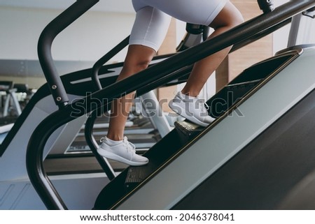 Cropped up photo shot young strong skinny sporty athletic sportswoman woman in white sportswear warm up train run on a treadmill climber stairs machine in gym indoor Workout sport motivation concept Royalty-Free Stock Photo #2046378041