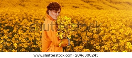 Portrait of red haired women dressed in trendy fall orange trench coat in colourful orange field. Fashion clothes autumn look