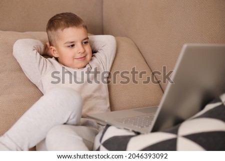 Child at home watching cartoon on the computer. Little boy and a laptop. Modern kid and education technology.
