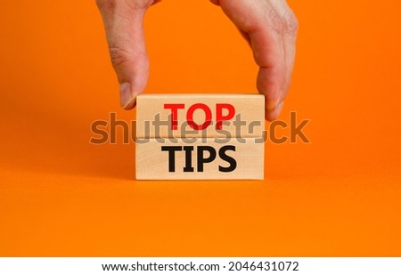 Top tips symbol. Concept words Top tips on wooden blocks on a beautiful orange background. Businessman hand. Business and Top tips concept, copy space.