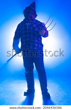 A vertical shot of a person in a scary scarecrow costume in a blue room