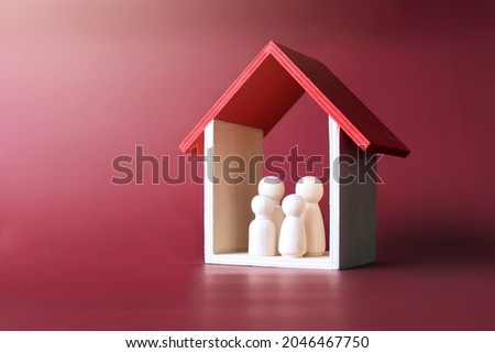 Family care, protection and insurance concept. Wooden dolls family inside a house. Royalty-Free Stock Photo #2046467750