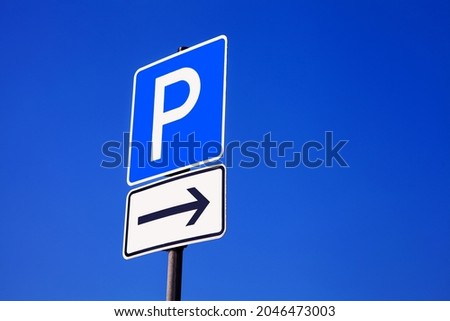 A shot of a blue parking sign and an arrow showing to the right isolated on a blue background