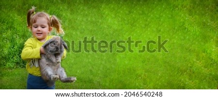cute caucasian baby girl having fun with rabit, back yard vacation, copy space text