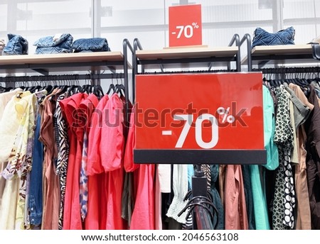 Red stand with big 70 percent discount price in shopping center. Advertising of Black Friday cheap clothes.Season sale concept with clothes hangers on background.