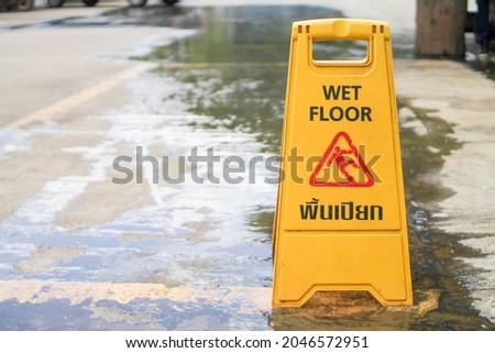 Yellow signs warning of Wet Floor and Caution to Slip are placed on wet walkways to warn tourists to walk with caution. The concept of installing prominent warning signs for safety.