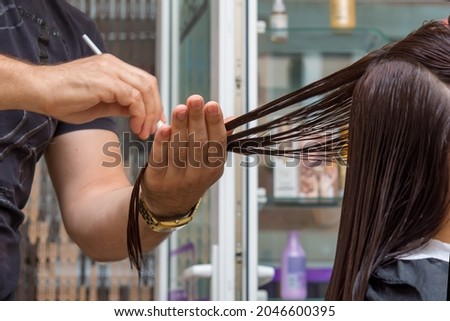 Professional Hairdresser Making Haircut Female Client. Close-up picture of hair stylist's hands. Professional scissors, brush on workplace. Hairdresser tools, equipment.