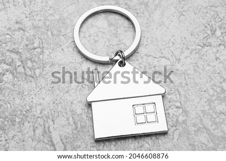 Stylish house shape keychain on grunge background