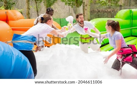 Game of funny friends in soap suds on an inflatable trampoline. High quality photo