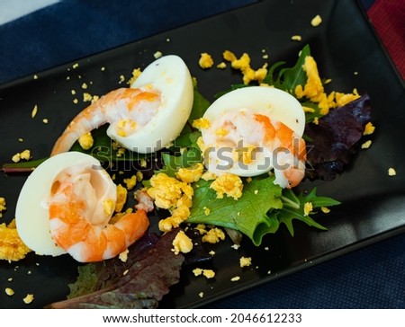 Delicious dish of Mimosa eggs with peeled tiger prawns and herbs