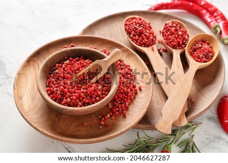Bowl with red peppercorns on light background