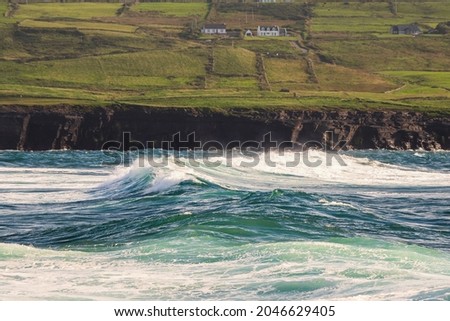 Powerful waves crushing against Cliffs and rough stone coastline of West coast of Ireland. Doolin area. County Clare. Ocean power and rugged Irish coastline. Green fields in the background Royalty-Free Stock Photo #2046629405