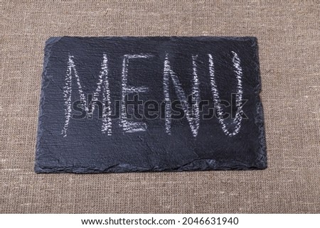 menu. an inscription on a black stone in white chalk. taken on burlap