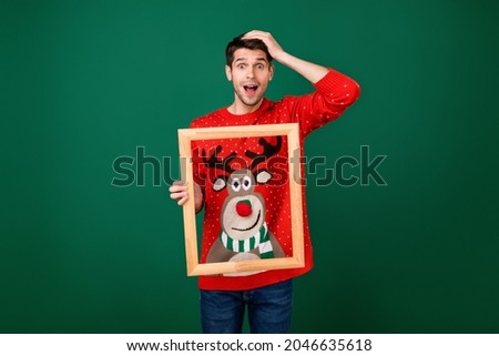 Photo of young excited man hold wooden frame picture wear designed sweater new year isolated over green color background