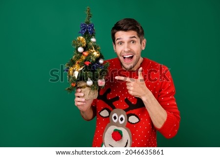 Photo portrait man wearing funny sweater pointing finger xmas tree staring crazy isolated green color background