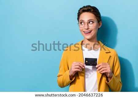 Photo of young woman happy positive smile hold credit card look empty space isolated over blue color background