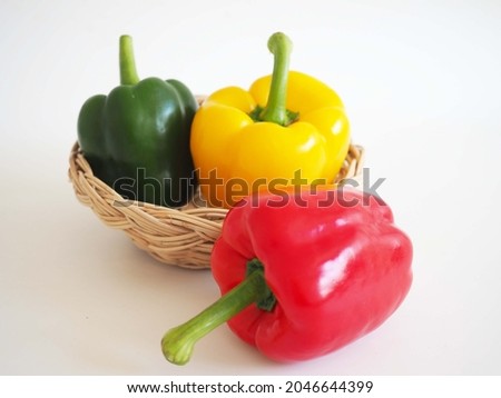 Three colors sweet pepper in wood basket on white background. closeup photo, blurred.